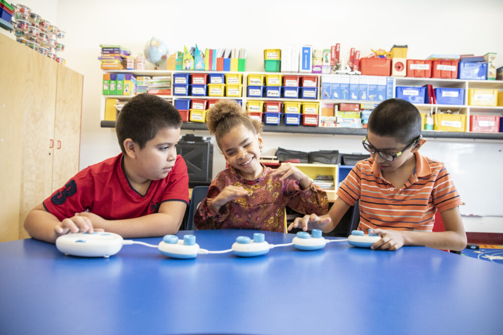 Three students sitting at at classroom table working with the code jumper.