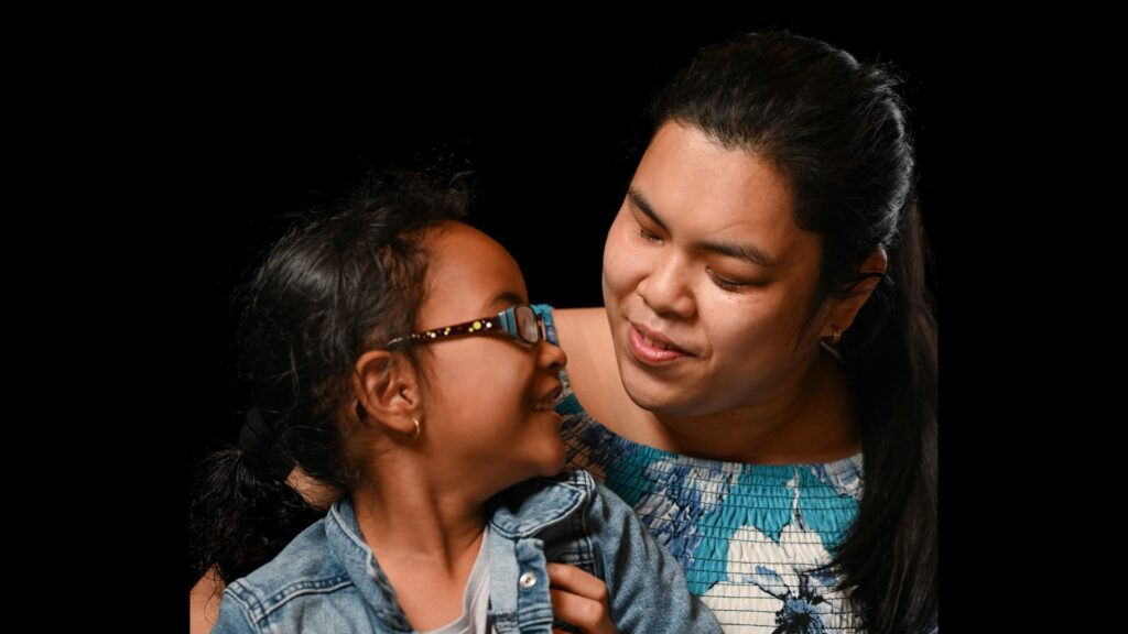 Mother and child embrace; adult has a light forehead scar.